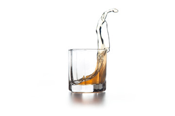 Whiskey splash in glass with ice on light background..
