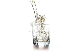 Whiskey pouring into glass with ice on light background..