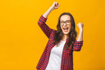 Winning success woman happy ecstatic celebrating being a winner. Dynamic energetic image of multiracial Caucasian Asian female model isolated on yellow background waist up.
