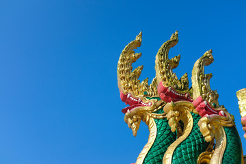 Thai Naka, big snake, serpent statue on clear bright blue sky. Mythical creature in Buddhism belief. Traditional Thai style architecture