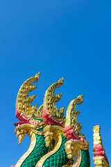 Fototapeta na wymiar Thai Naka, big snake, serpent statue on clear bright blue sky. Mythical creature in Buddhism belief. Traditional Thai style architecture