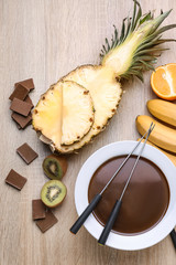 Bowl with tasty chocolate fondue and fruits on table