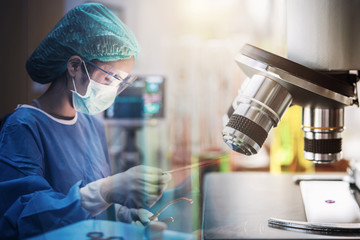 Scientist or doctor working in the operating room with microscope and glassware, medical and science research and development concept