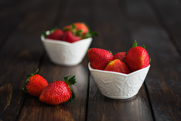 Fresh strawberries in white bowl on old wooden table