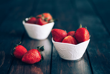 Fresh strawberries in white bowl on old wooden table