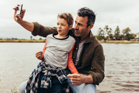 Father and son clicking a selfie near a lake