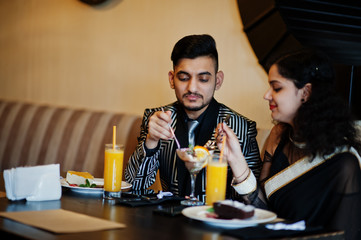 Lovely indian couple in love, wear at saree and elegant suit, posed on restaurant.