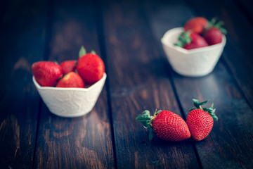 Fresh strawberries in white bowl on old wooden table
