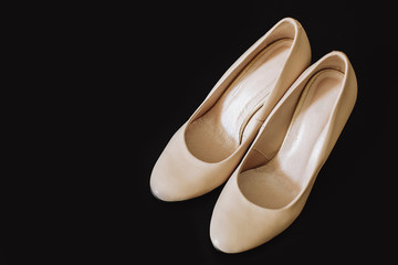 Beautiful new female shoes of beige color on a black background with a place for the text.