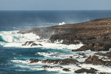 Fototapeta na wymiar Ocean surf. Big waves crash against stones. Volcanic rock.