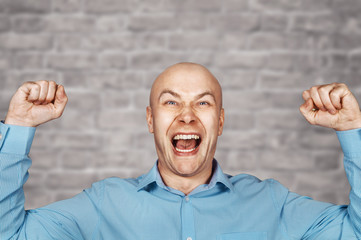 Naklejka premium Portrait White bald guy in blue shirt on white Brick wall background showing thumbs up and smiling