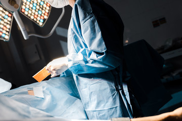 cropped view of nurse in uniform and latex gloves putting on strip in operating room