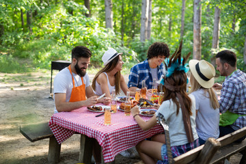 Happy friends camping and having a barbecue in nature