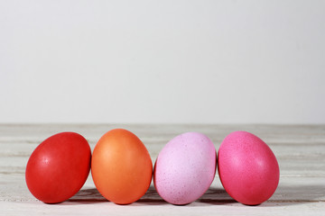 Easter Eggs concept. Line off red, pink, orange, purple  Easter eggs on white wooden table. Blank copy space, side view, background, row, set
