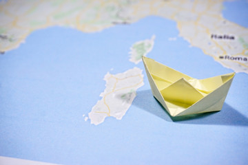 Travelling around the world concept using origami paper ship and map 
