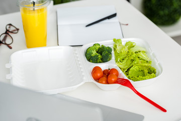 tasty organic vegetables near plastic fork and notebook with pen