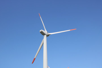 Wind turbines for electric power production on beautiful sunny summer with blue sky. Green ecological power energy generator.