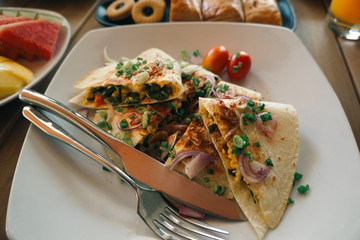 Breakfast table with omelet sandwich, fresh fruit, cookies. top view