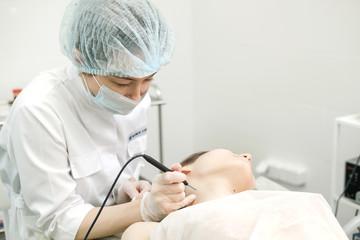 Medical treatment removal of birthmark from female patient's neck. Female dermatologist surgeon using electrocautery for removing mole. Radio wave electrocoagulation remove method. Close up