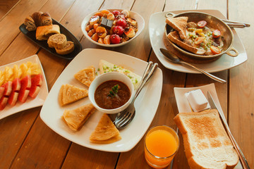 Breakfast table with omelet sandwich, fresh fruit, cookies and Shahi Paneer. top view
