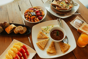 Breakfast table with omelet sandwich, fresh fruit, cookies and Shahi Paneer. top view