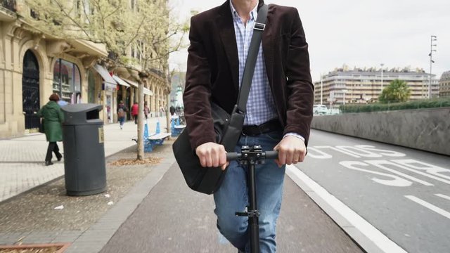 Businessman commuting to work on micro scooter