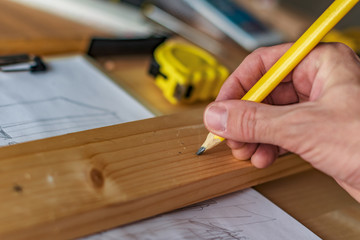 Fototapeta na wymiar Carpenter marking pine wood plank for cutting