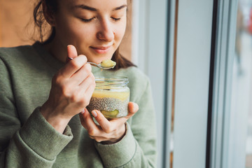 Close-up of a woman eating a yogurt with fruit on a cafe background