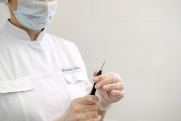 Female dermatologist surgeon preparing a professional electrocautery for removing mole. Radio wave electrocoagulation remove method