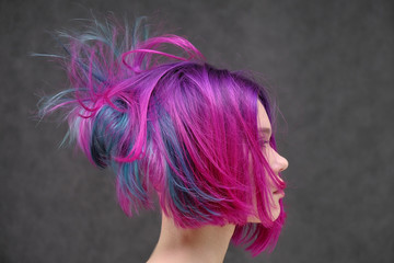 Concept Portrait of a punk girl, young woman with chic purple hair color in studio close up on a colorful background with fluttering hair.