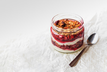 Fototapeta premium Summer fruit red berry breakfast. Healthy cherry split breakfast with cream cheese, granola, nuts and dried fruits white chocolate. In mason jar, on table. Copy space