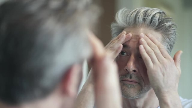 Mature man looking at himself in mirror