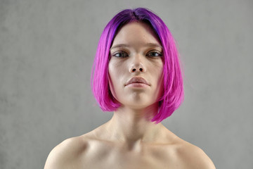 Naklejka premium Concept Portrait of a punk girl, young woman with chic purple hair color in studio close up on a colorful background with fluttering hair.