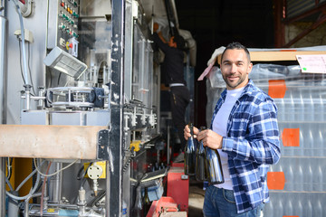 young man wine maker working filling wine bottle with automatic bottling machine