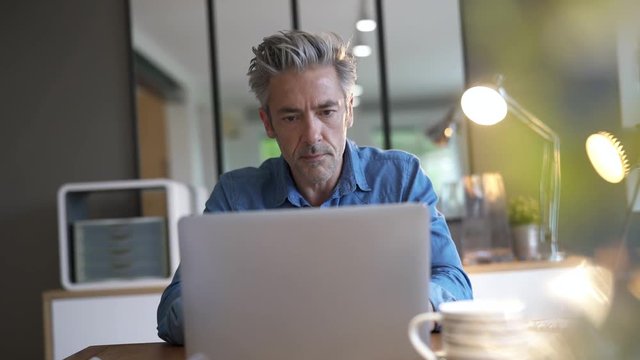 Mature man working from home at the weekend