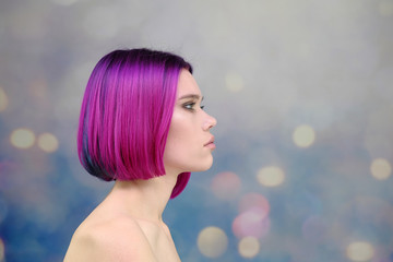 Concept Portrait of a punk girl, young woman with chic purple hair color in studio close up on a colorful background with fluttering hair.