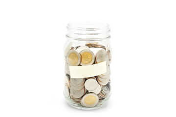 New Thai Baht coins in a glass jar with blank label, isolated on white background. Business and finance concept.