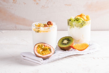 Two glasses with  yogurt and fresh fruit puree on white textured background. 