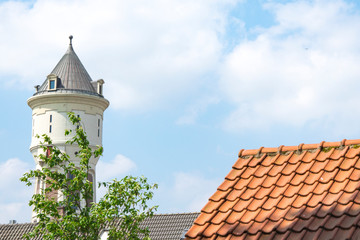 white water tower, orange roof tiles in Roosendaal, The Netherlands. Blue sky, space for text