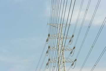 Fototapeta premium high voltage power pylons against blue sky and sun rays 