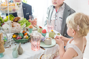 Obraz na płótnie Canvas Anonymous children enjoy Easter breakfast together at family table. Polish Easter celebration.