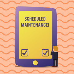 Conceptual hand writing showing Scheduled Maintenance. Concept meaning predetermined maintenance carried out at regular time Businessman Standing and Gesturing on Screen Tablet Device