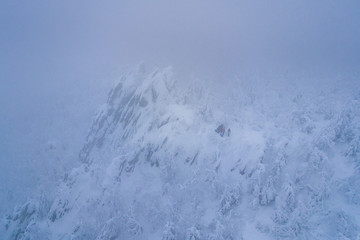 Aerial shot of group of people standing on the mountain top in winter mist