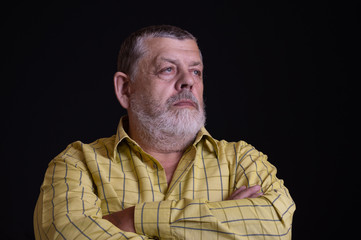 Obraz premium Nice low key portrait of a thoughtful Caucasian, bearded senior man in yellow shirt