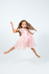 Fototapeta na wymiar Bambina con capelli lunghi castani e abito rosa che salta