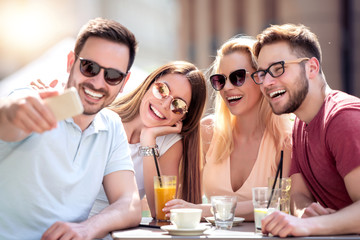 Group of four friends take selfie in cafe