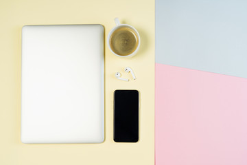 Laptop Coffee Workspace Pastel Background Flat Lay. Smartphone and Earphone on Minimal Office Stylish Copy Space Mockup. Blank Hipster Freelance Workspace. Coworking Creative Technology Lifestyle