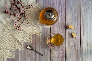 A teapot, a cup of tea and waffles on a wooden table