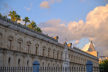 Fototapeta premium view of the Old Hospital of the Five Wounds at sunset with palms tree - Seville Spain.