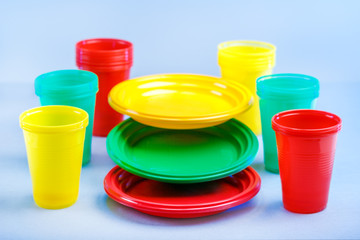 Colorful plastic dishes on blue background with copy space.